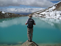 A hiker gazes at an Emerald Lake at Tongariro